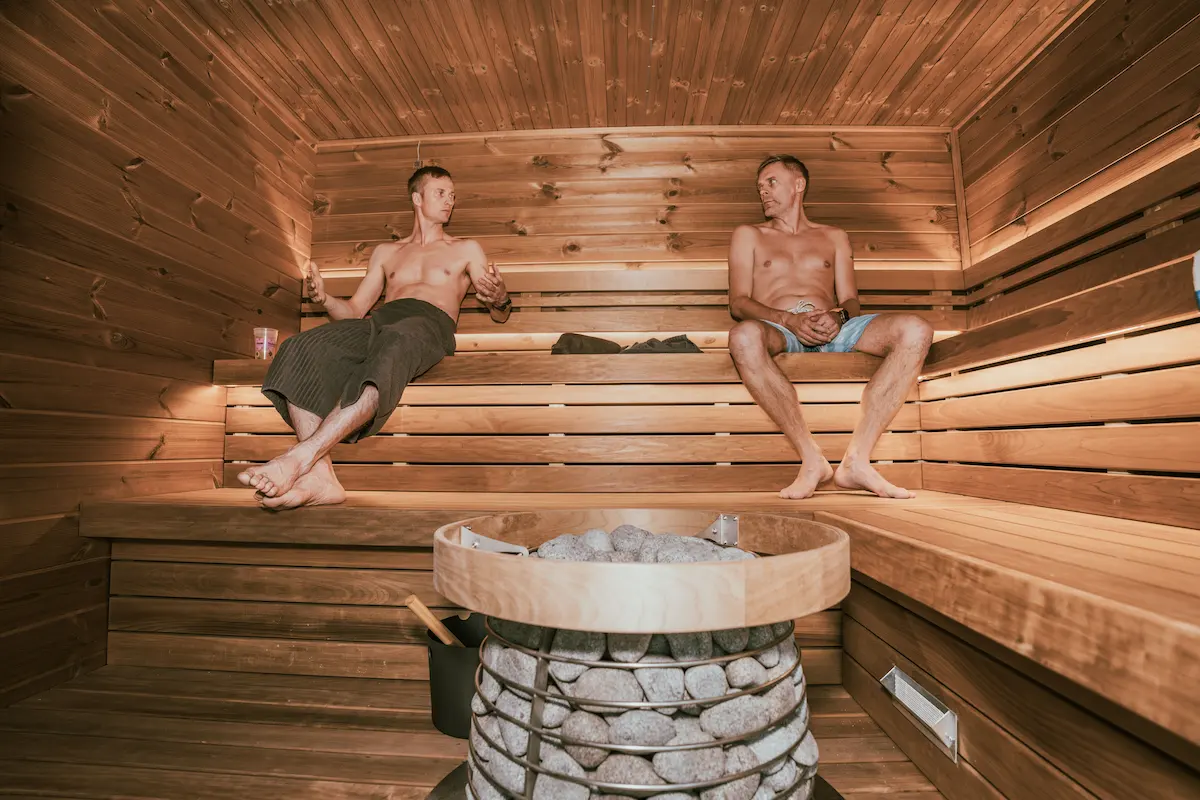 Two men relaxing on the cedar benches inside the sauna